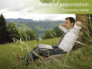 A Man Sitting In The Grass With A Laptop PowerPoint Template