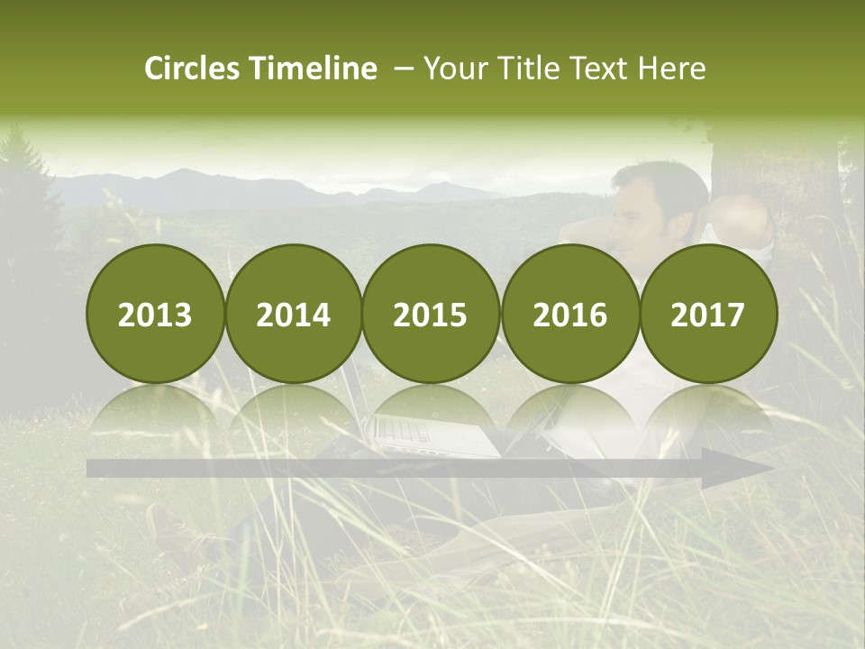 A Man Sitting In The Grass With A Laptop PowerPoint Template