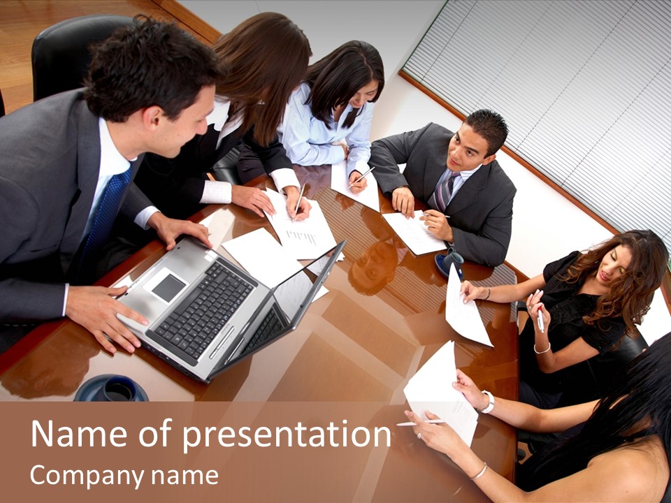 A Group Of People Sitting Around A Conference Table PowerPoint Template