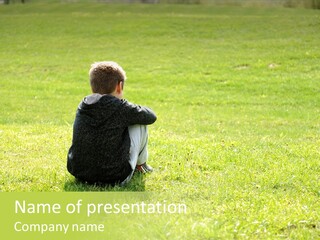 A Young Boy Sitting On The Grass In A Park PowerPoint Template