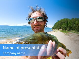 A Man Holding A Large Fish On A Beach PowerPoint Template