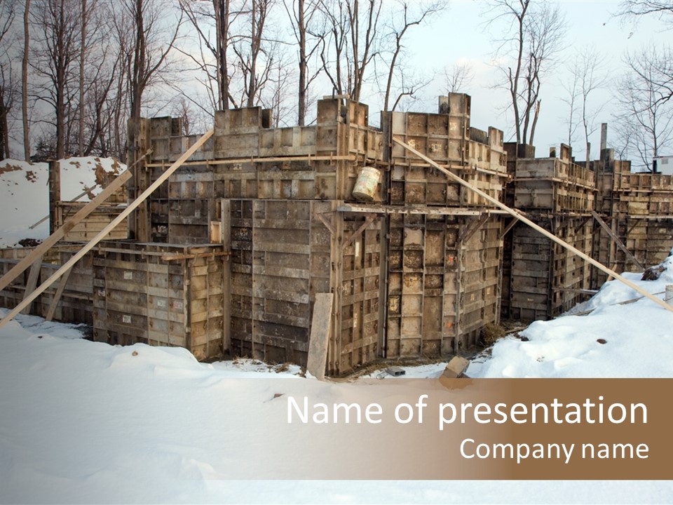 New Home Construction Site In The Winter, With Snow In The Foreground And Woods In The Background PowerPoint Template
