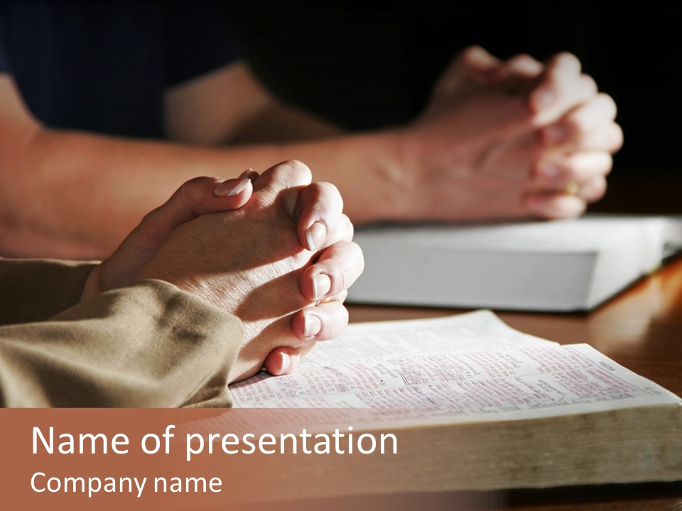 A Couple Prays Together At A Table As Their Hands Rest Upon Their Holy Bibles (Shallow Focus). PowerPoint Template