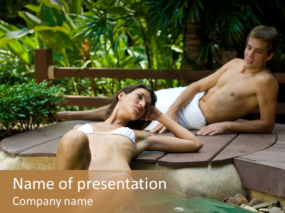 A Young Attractive Couple Lying By A Jacuzzi In Tropical Setting PowerPoint Template