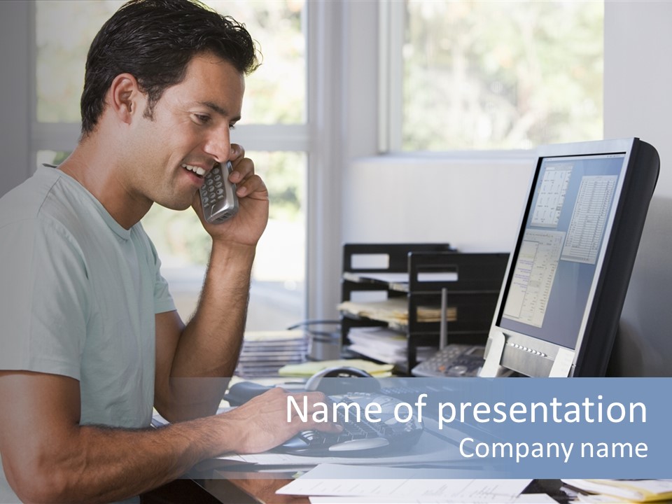 Man In Home Office On Telephone Using Computer And Smiling PowerPoint Template