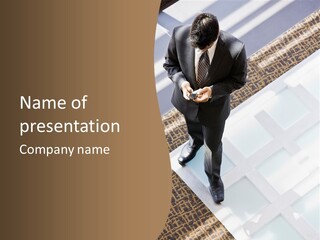 A Man In A Suit Is Looking Down At His Cell Phone PowerPoint Template