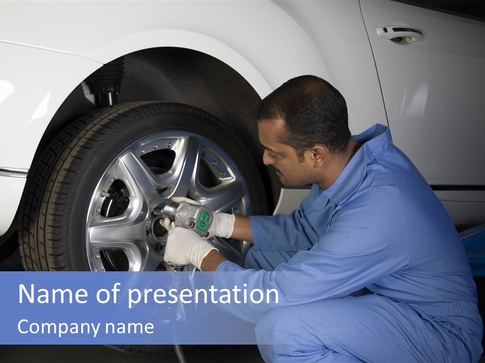 Auto Mechanic Removing Wheel Of A Car In A Workshop PowerPoint Template