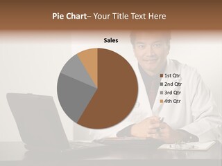 Asian American Male Doctor Sitting At Desk With Charts And Laptop Computer Looking At Viewer. PowerPoint Template