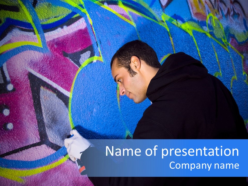 A Man In A Hoodie Writing On A Wall With Graffiti PowerPoint Template