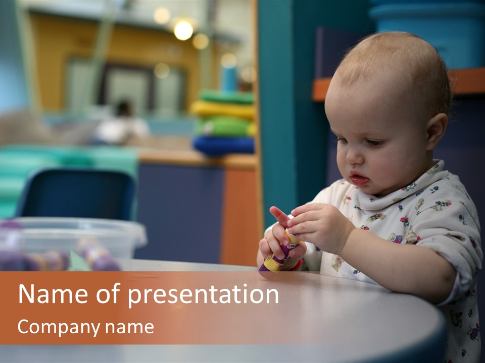 A Baby Sitting At A Table Playing With A Toy PowerPoint Template