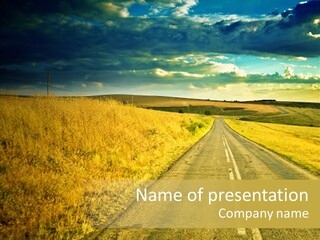A Road Going Through A Field With A Cloudy Sky In The Background PowerPoint Template