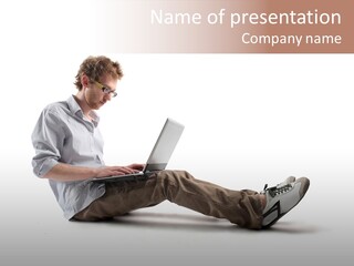 A Man Sitting On The Floor Using A Laptop Computer PowerPoint Template