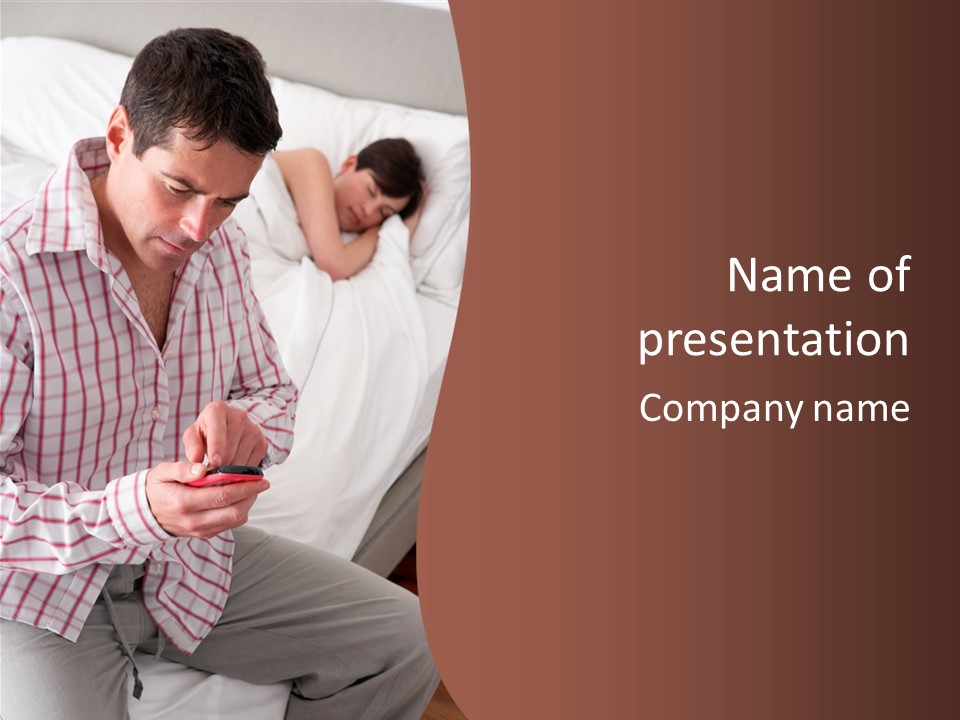A Man Sitting On A Bed Looking At His Cell Phone PowerPoint Template