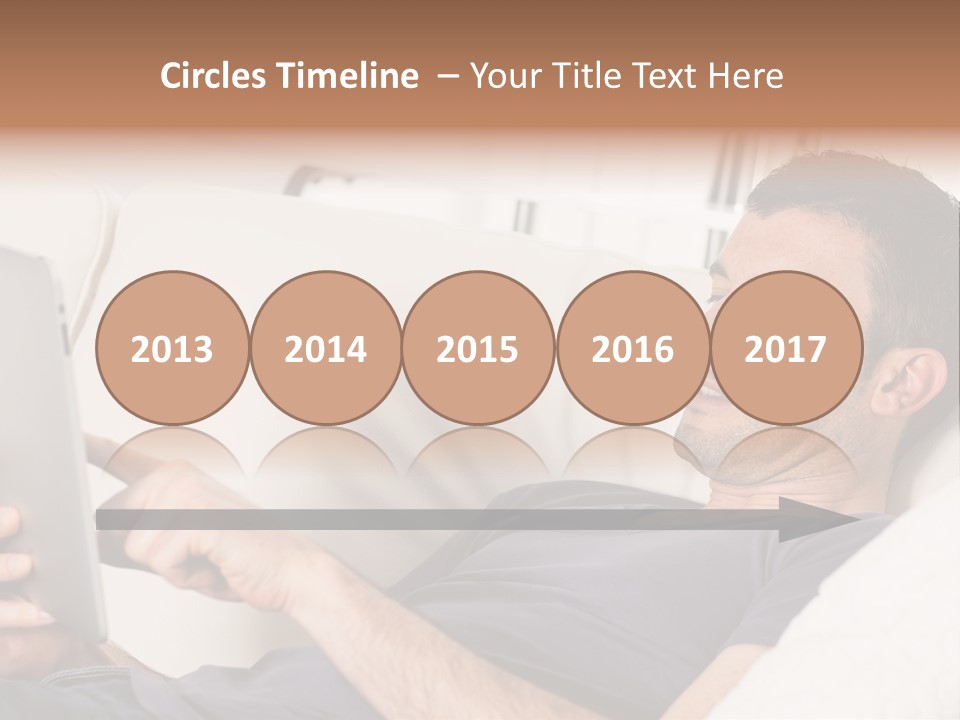 A Man Sitting On A Couch Looking At A Tablet PowerPoint Template