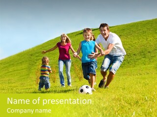 A Family Playing With A Soccer Ball In A Field PowerPoint Template