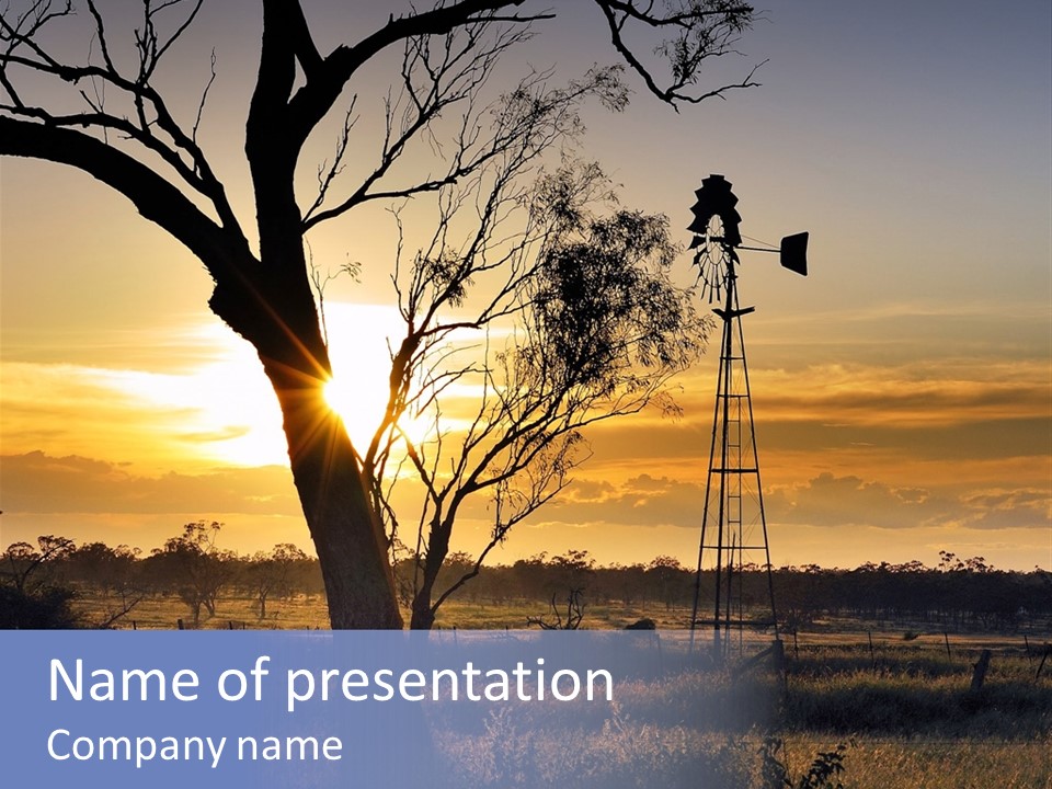 A Windmill And A Tree With The Sun Setting In The Background PowerPoint Template