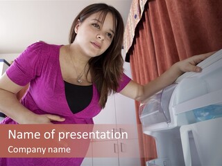 A Woman Standing Next To A Refrigerator In A Kitchen PowerPoint Template