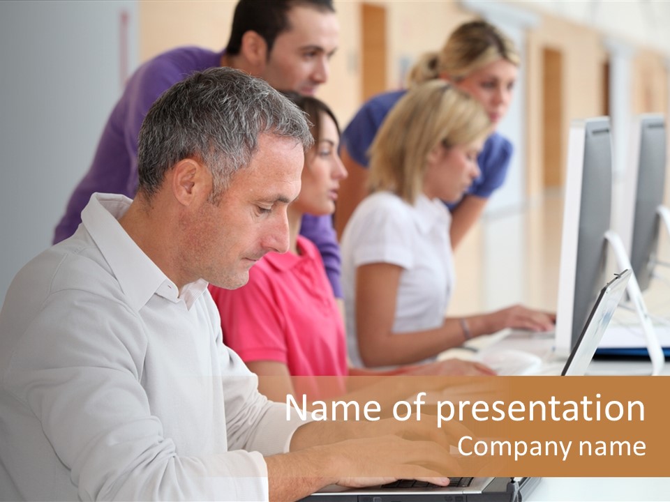 A Group Of People Sitting At A Table With Computers PowerPoint Template