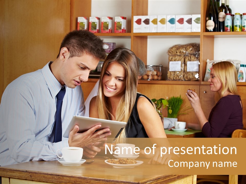 A Man And Woman Sitting At A Table Looking At A Tablet PowerPoint Template