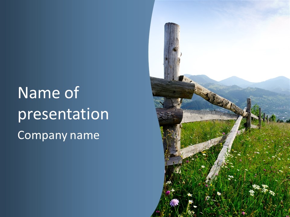 A Wooden Fence In A Grassy Field With Mountains In The Background PowerPoint Template