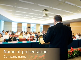 A Man Standing At A Podium In Front Of A Crowd Of People PowerPoint Template
