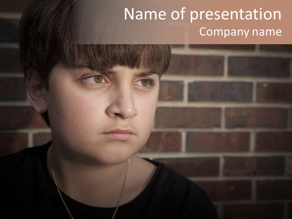 A Young Boy Is Looking At The Camera With A Brick Wall Behind Him PowerPoint Template