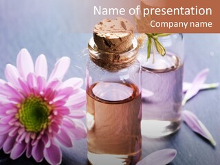 A Bottle Of Oil And A Flower On A Table PowerPoint Template