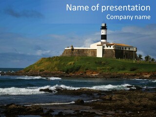 A Lighthouse Sitting On Top Of A Green Hill Next To The Ocean PowerPoint Template