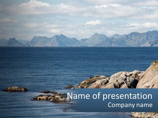 A Lighthouse On A Rocky Shore With Mountains In The Background PowerPoint Template