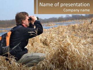 A Man Sitting In A Field Looking Through Binoculars PowerPoint Template