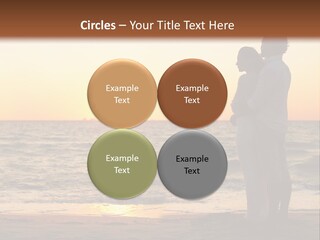 Two People Standing On A Beach At Sunset PowerPoint Template