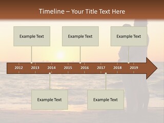 Two People Standing On A Beach At Sunset PowerPoint Template