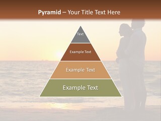 Two People Standing On A Beach At Sunset PowerPoint Template