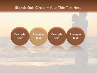 Two People Standing On A Beach At Sunset PowerPoint Template