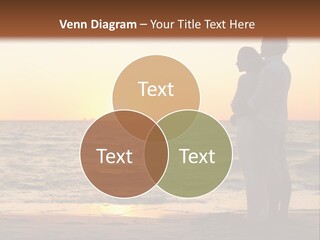 Two People Standing On A Beach At Sunset PowerPoint Template