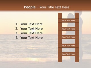 Two People Standing On A Beach At Sunset PowerPoint Template