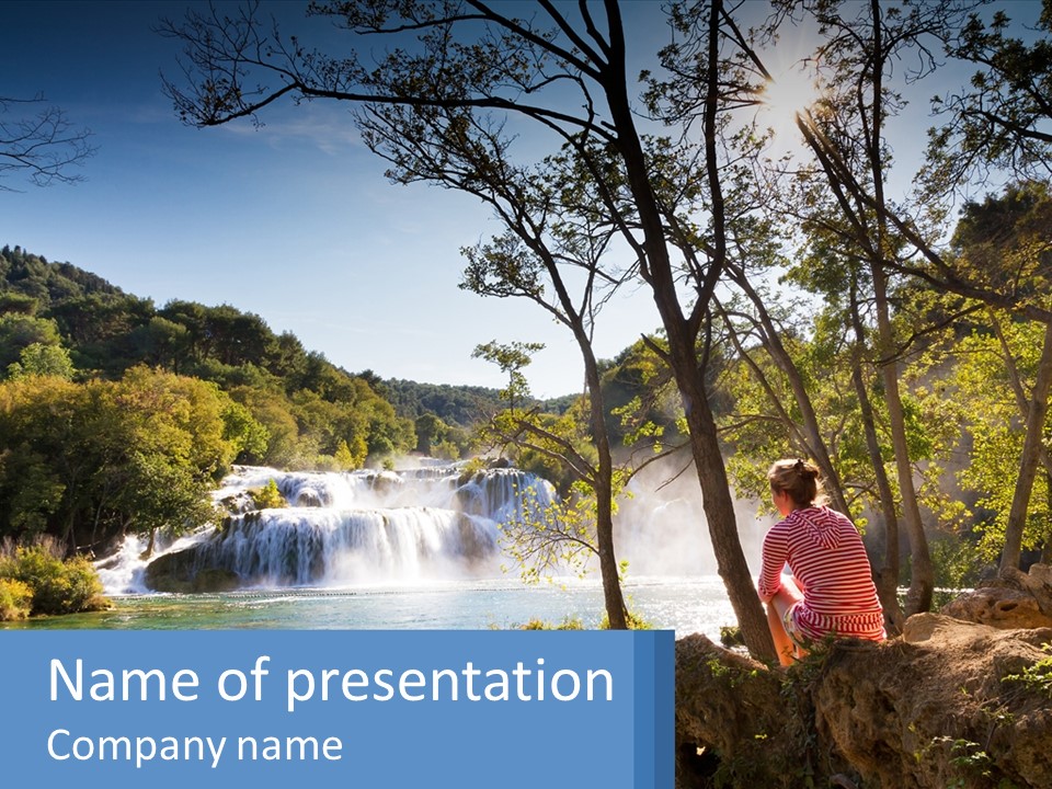 A Woman Sitting On A Rock Looking At A Waterfall PowerPoint Template