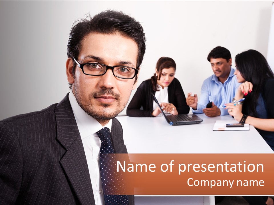 A Man In A Suit And Tie Sitting At A Table With A Group Of People PowerPoint Template