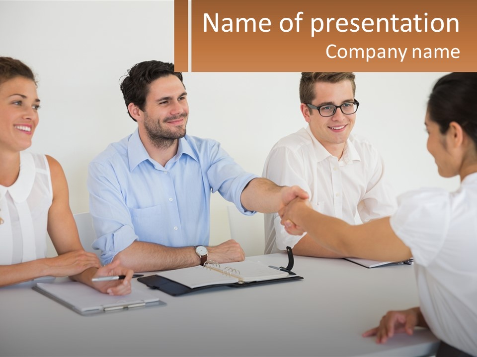 A Group Of People Sitting Around A Table Shaking Hands PowerPoint Template