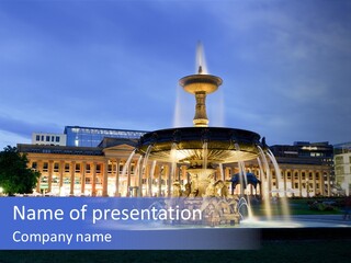 A Fountain In Front Of A Building At Night PowerPoint Template