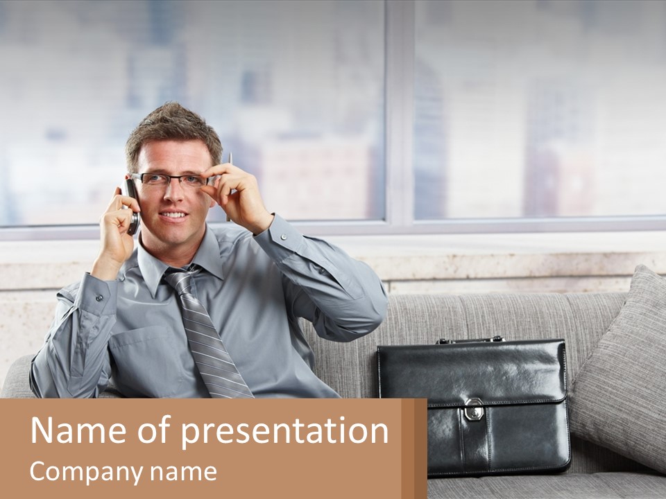 A Man Sitting On A Couch Talking On A Cell Phone PowerPoint Template