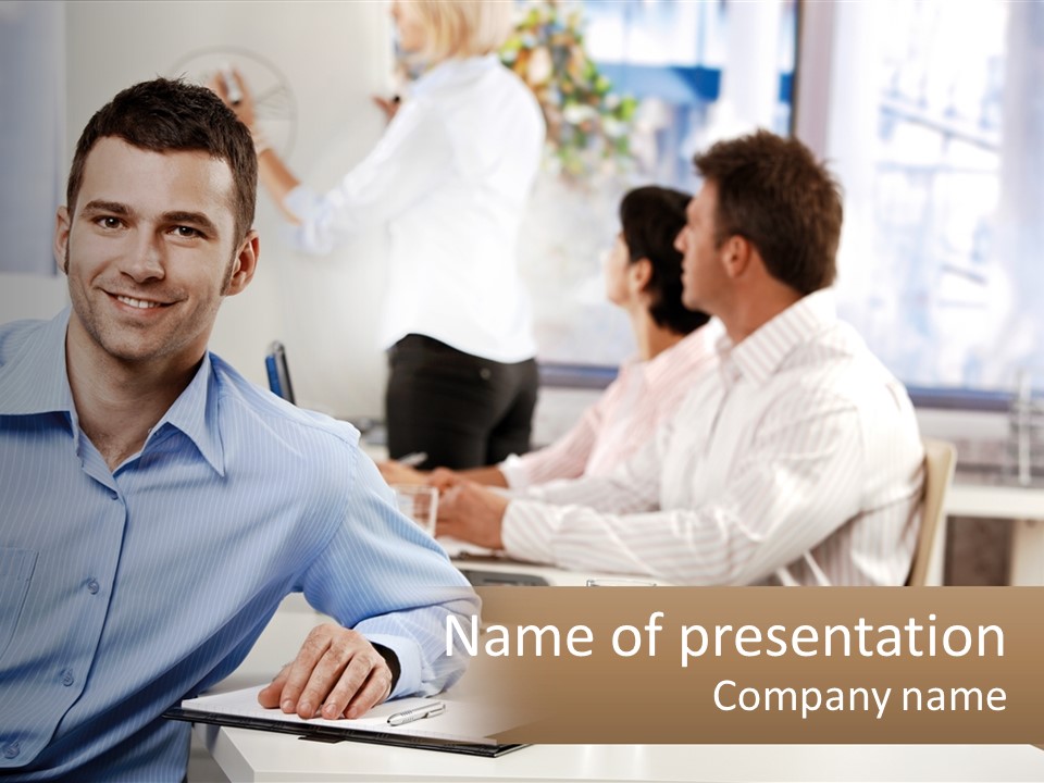 A Man Sitting At A Desk In Front Of A Group Of People PowerPoint Template