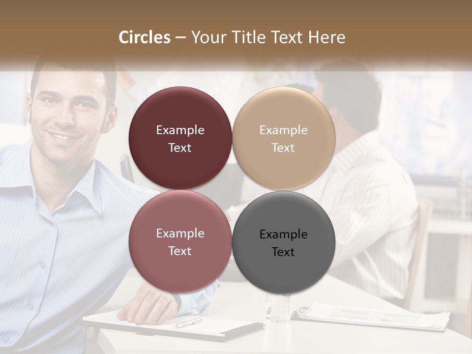 A Man Sitting At A Desk In Front Of A Group Of People PowerPoint Template