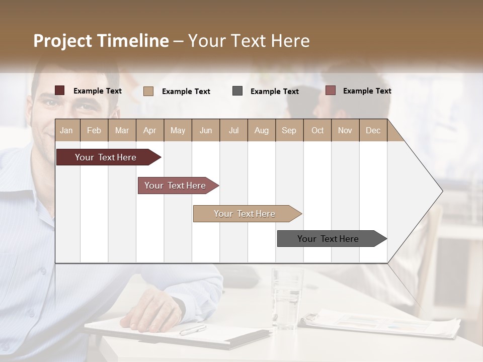 A Man Sitting At A Desk In Front Of A Group Of People PowerPoint Template