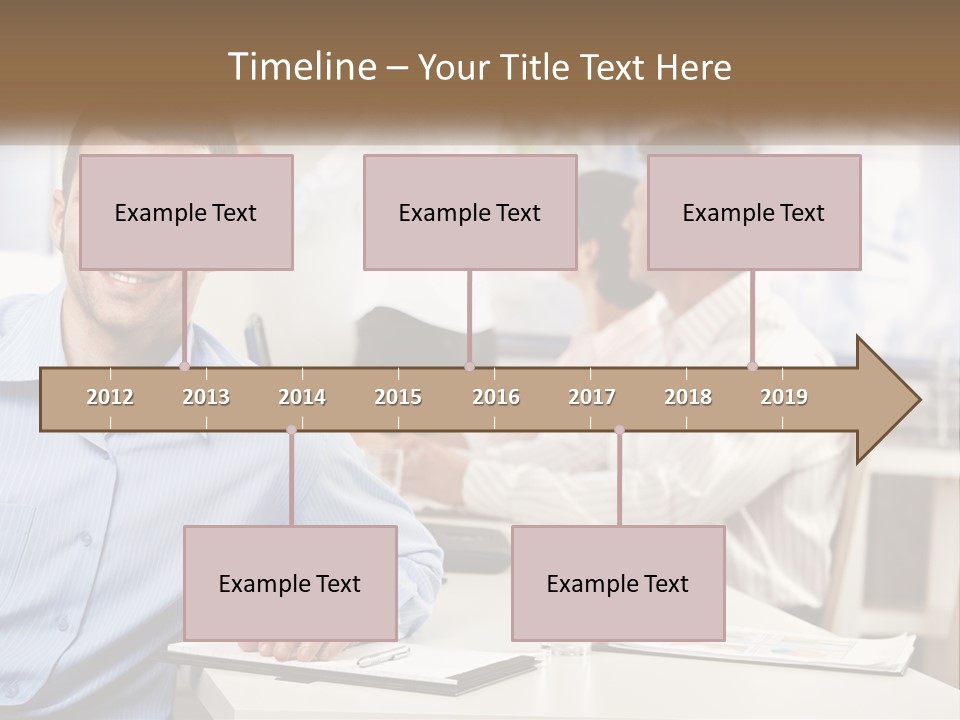 A Man Sitting At A Desk In Front Of A Group Of People PowerPoint Template