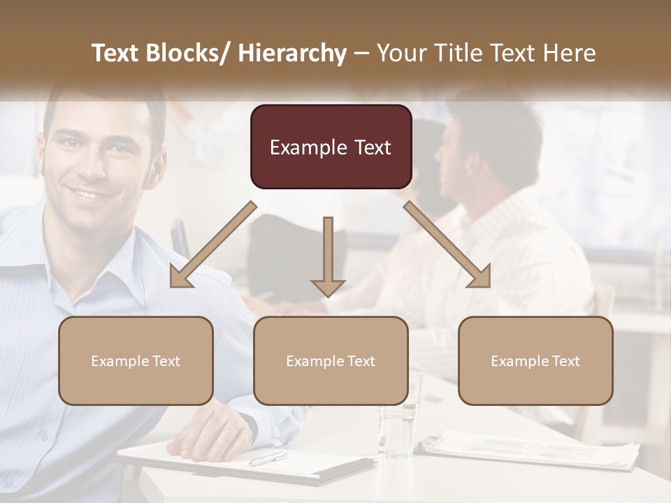 A Man Sitting At A Desk In Front Of A Group Of People PowerPoint Template