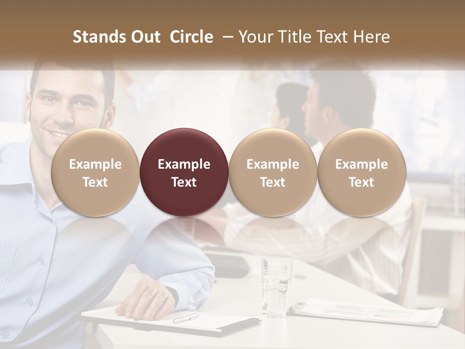 A Man Sitting At A Desk In Front Of A Group Of People PowerPoint Template