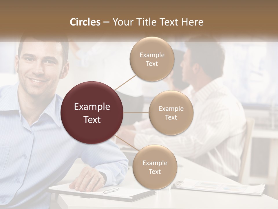 A Man Sitting At A Desk In Front Of A Group Of People PowerPoint Template