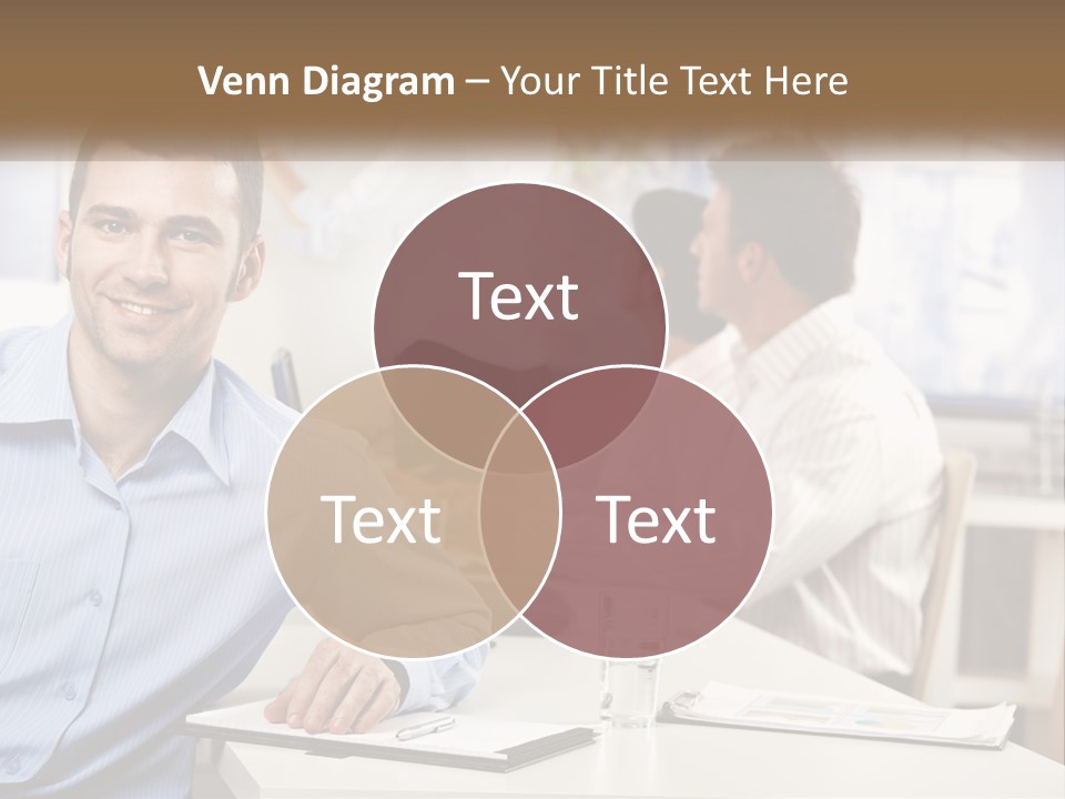 A Man Sitting At A Desk In Front Of A Group Of People PowerPoint Template
