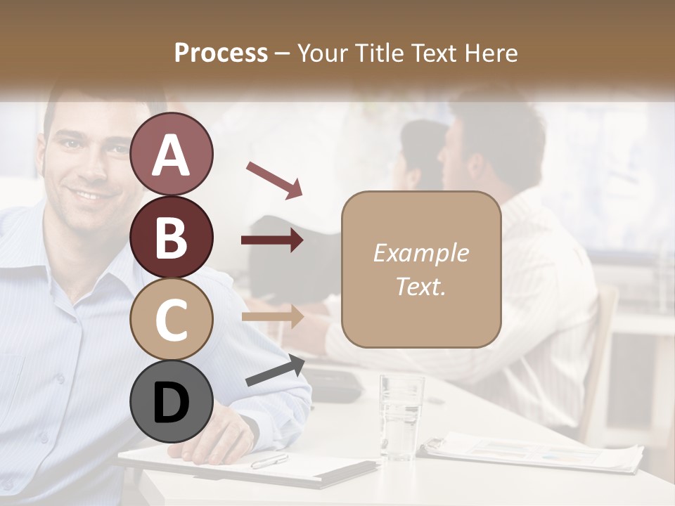 A Man Sitting At A Desk In Front Of A Group Of People PowerPoint Template